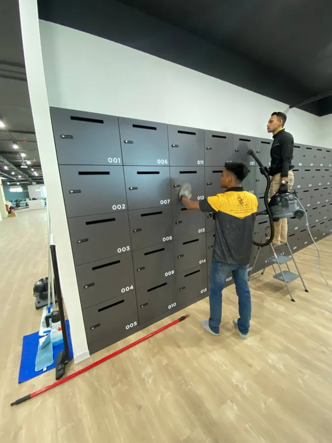 Two Yellowbee technicians cleaning a wall of office lockers, one on a ladder