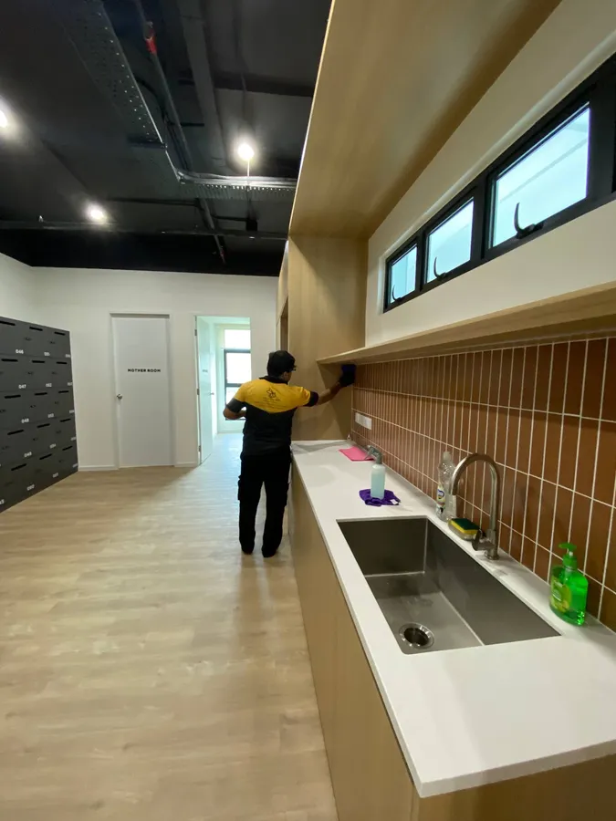 Yellowbee technician wiping a pantry ledge above the counter and sink