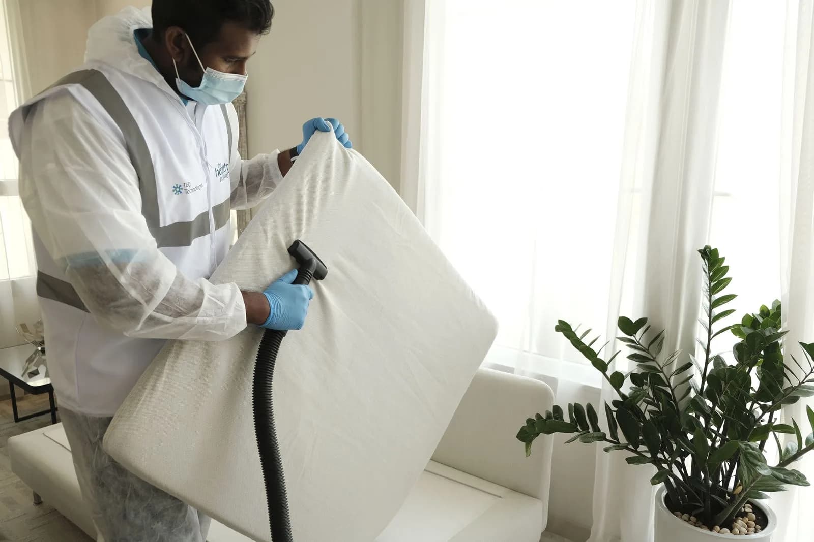 Pekerja cuci profesional guna mesin vacuum untuk deep cleaning perabot berlapis kain