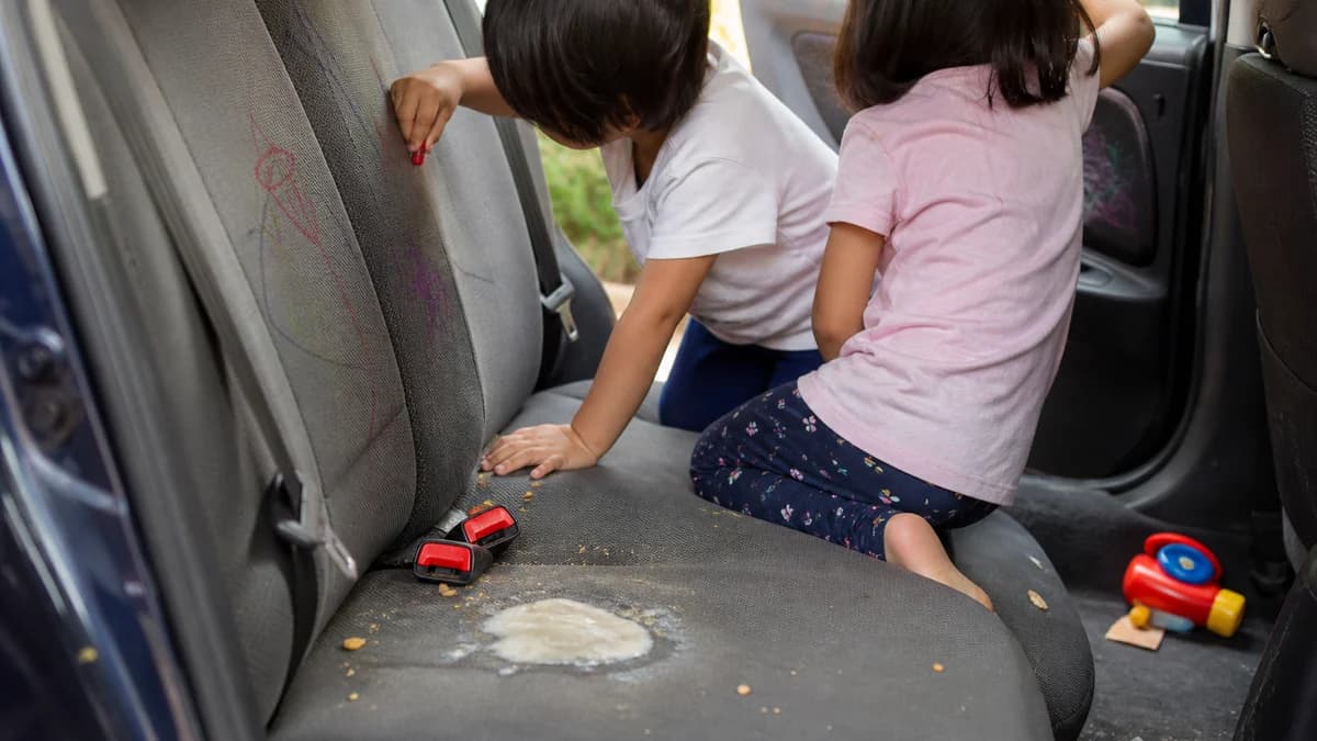 Kids playing in the back seat, crayon marks on the seat and a dried milk stain nearby