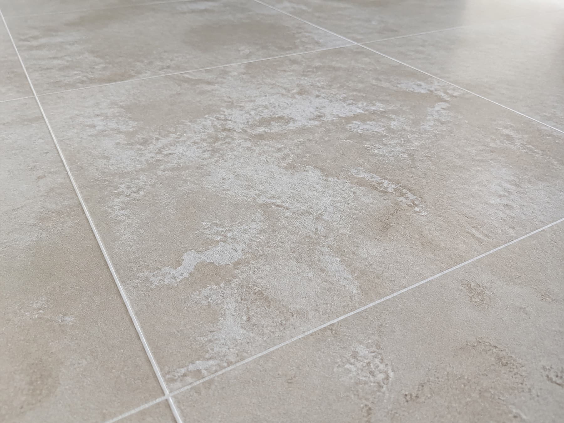 Dried cement haze forming a grayish film on ceramic tile after renovation work