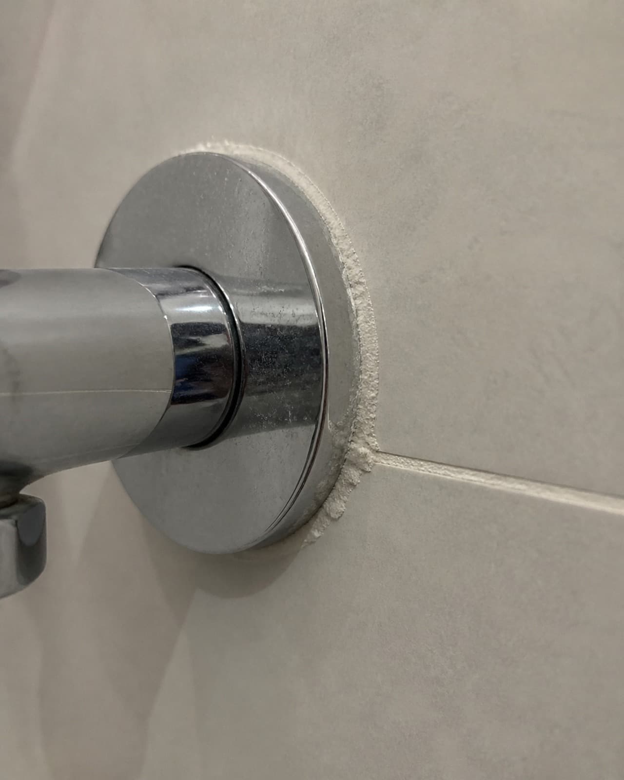 White mineral deposits around a bathroom tap base and adjacent tile grout line