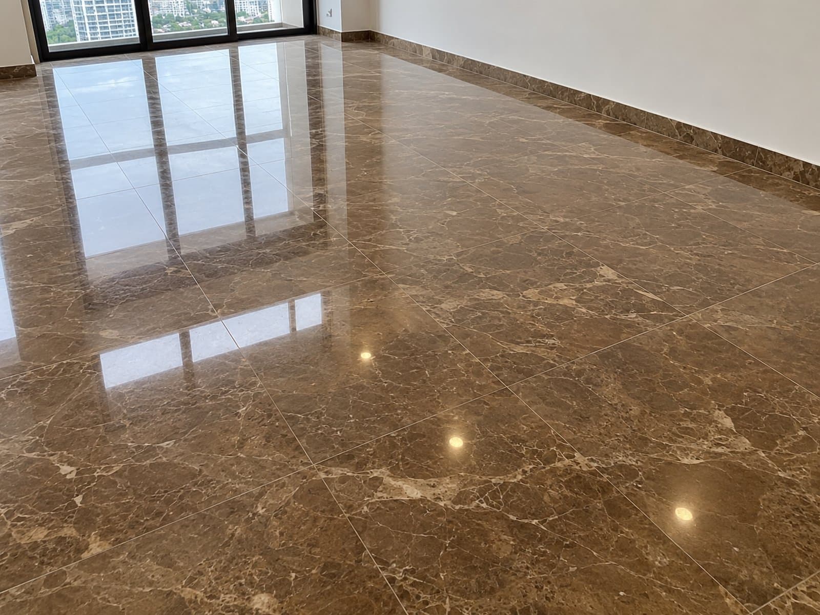 Polished brown marble with pale veining reflecting windows and ceiling lights