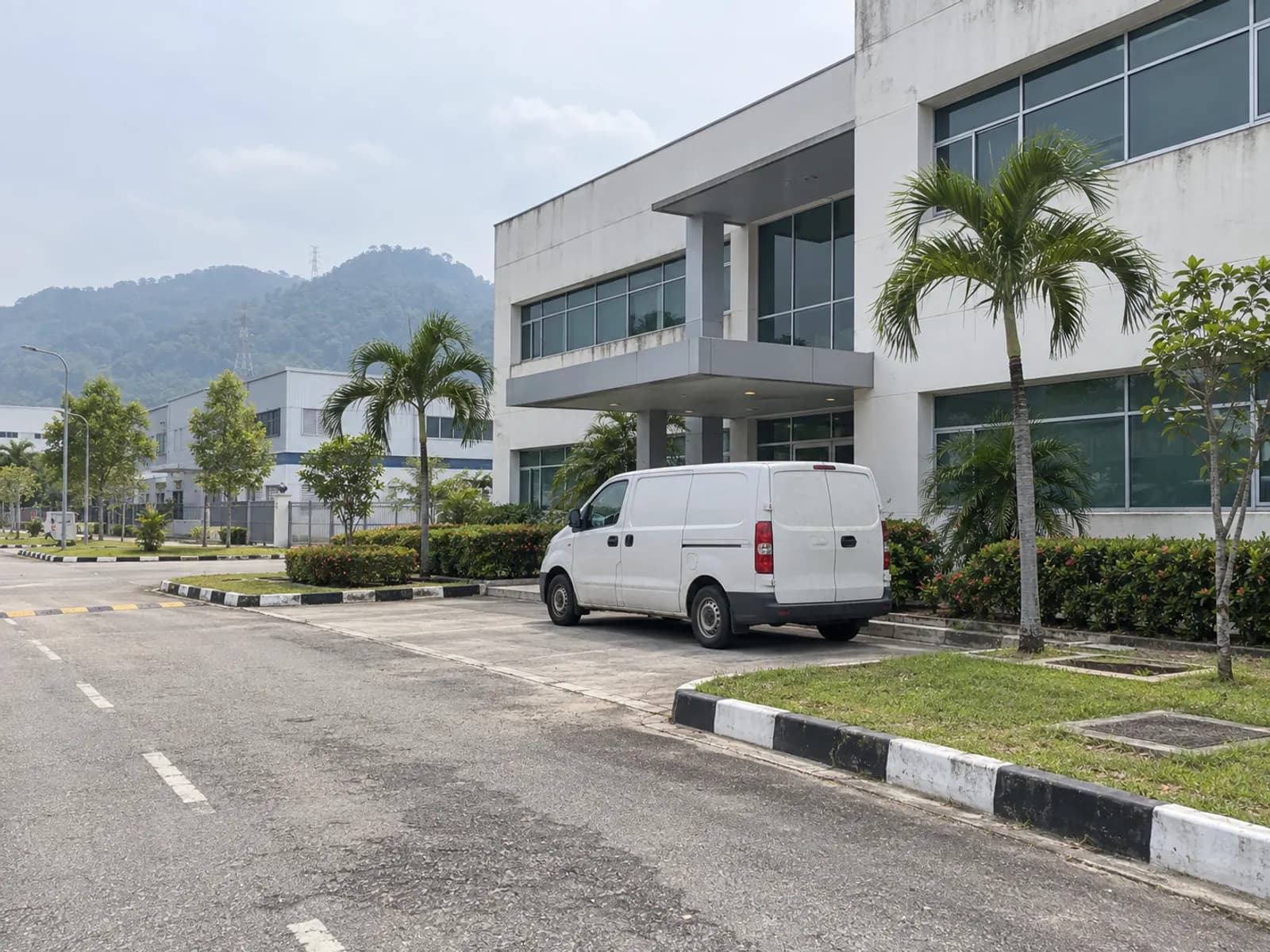 A plain industrial-park office block near Kulim with a Yellowbee work van parked outside